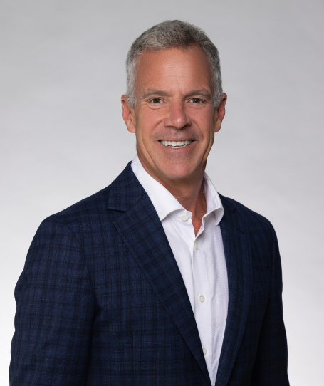 Man in a suit against a blue background with partially visible letters.